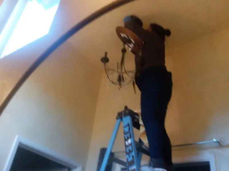 Electrician installing a chandelier in a Rosedale residence